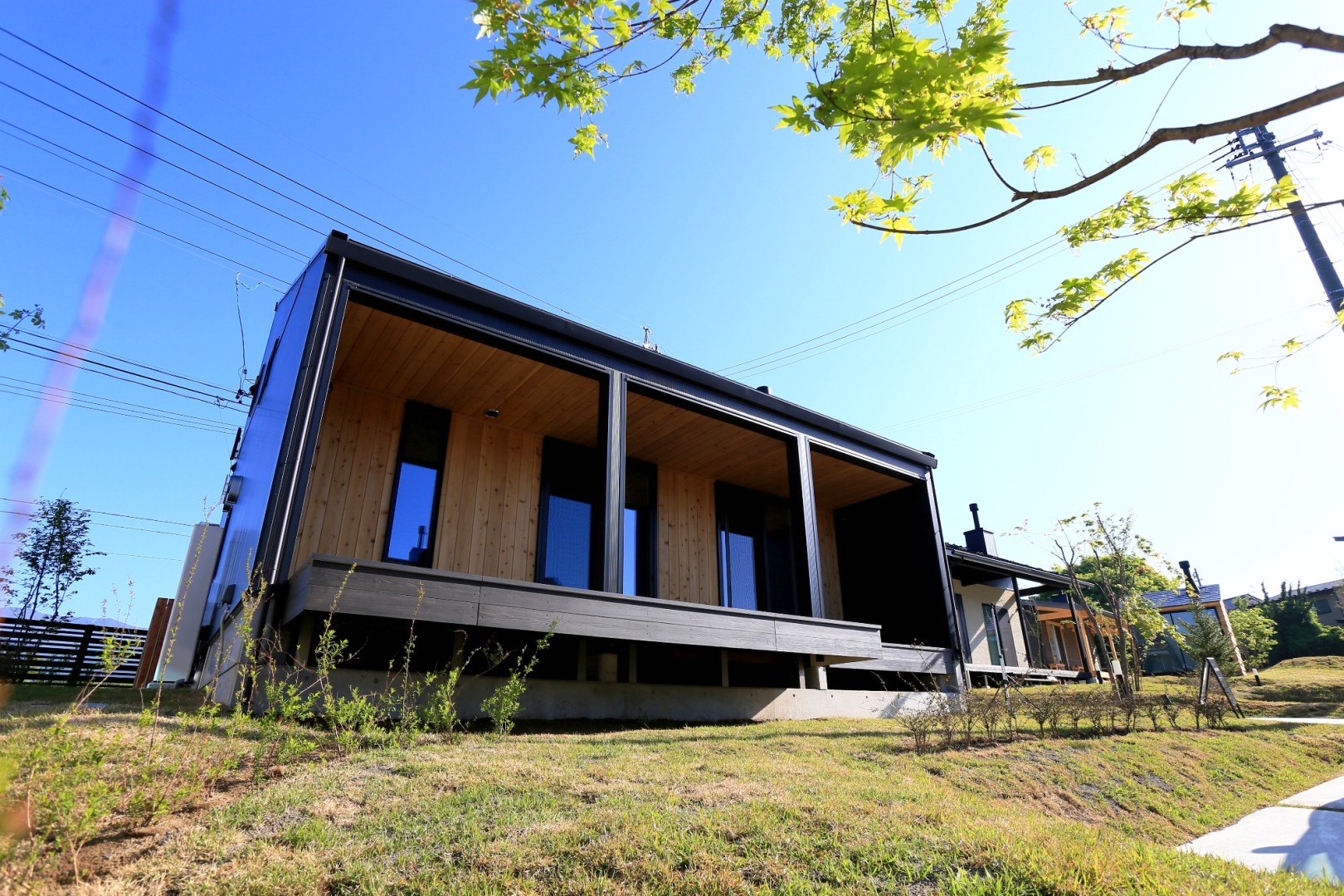黒のガルバリウムがシャープな屋根形状と相まって、デザインの良さを感じさせます。さらに玄関ドアは鏡面仕上げのブラック。板張りの壁面